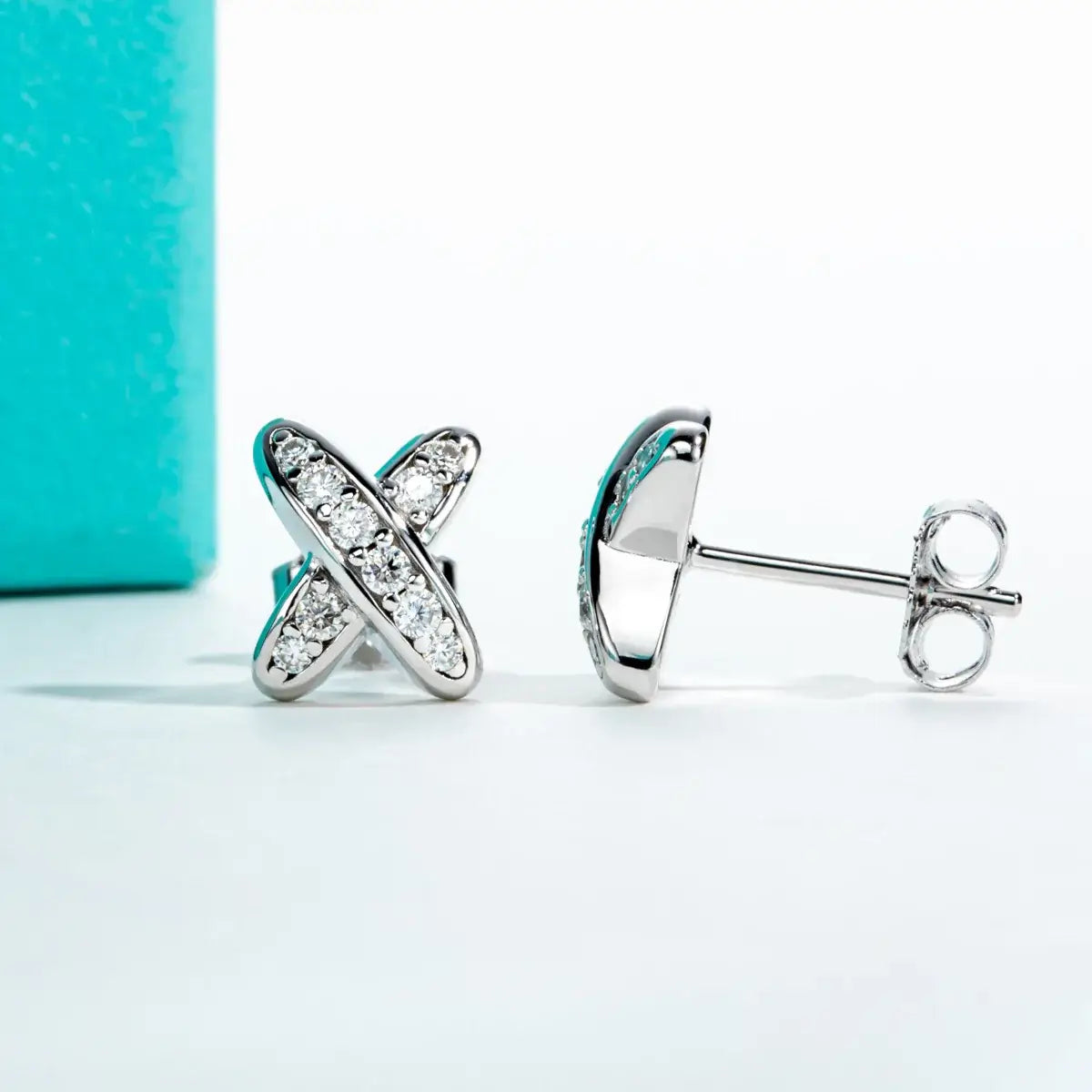 Moissanite diamond cross stud earrings in 925 sterling silver, elegantly displayed with a teal box.